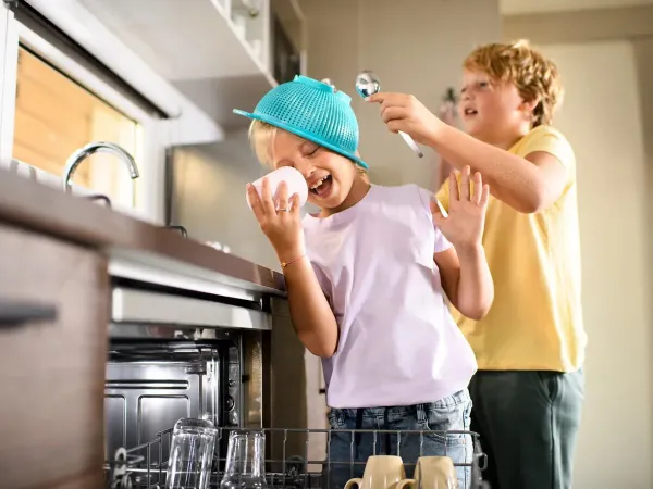 Children clear the dishwasher from the Roan mobile home Supreme with 2 bathrooms.