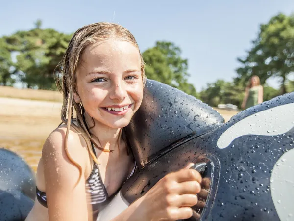 Girl with inflatable toys in natural pool at Roan camping The Schatberg.