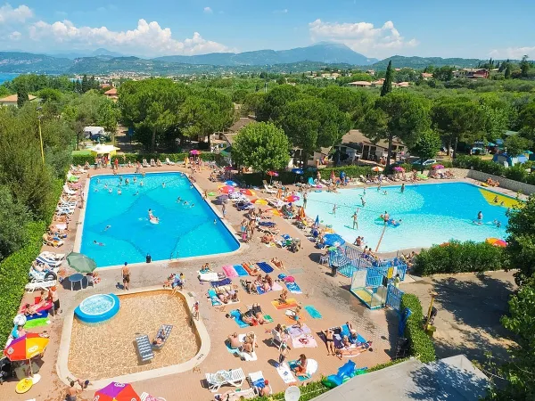 Overview of swimming pools with sun beds at Roan camping Cisano San Vito.