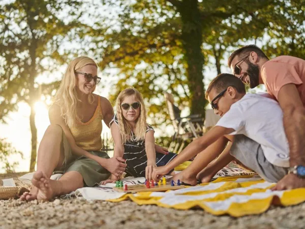 Family plays board game at Roan campsite Zelena Laguna.