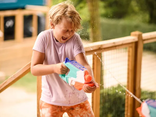 Child playing with water psitol at Roan camping Le Domaine de Beaulieu.