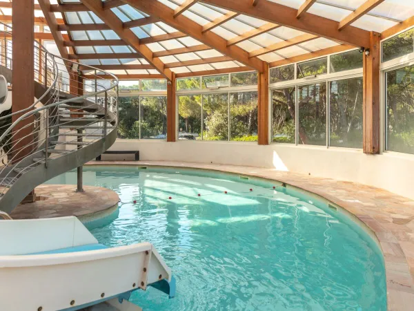 Indoor pool with slide at Roan camping La Baume.