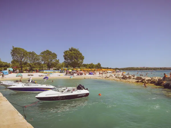 Beach with pier and boats at Roan camping Bi Village.