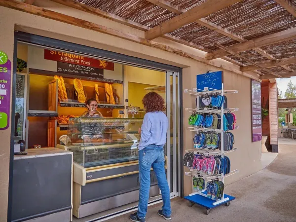 Guests pick up a fresh baguette from the bakery at Roan camping Les Dunes.