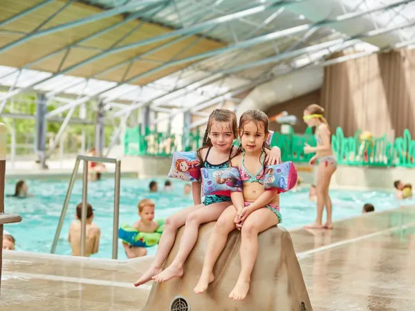 Two girls on a stone in the indoor pool at Roan camping Terspegelt.