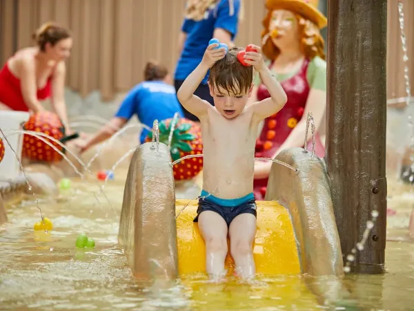 Little boy having water fun from the slide in paddling pool at Roan camping Terspegelt.