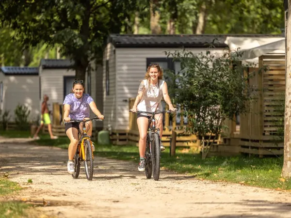 2 ladies cycle across Roan campsite Château de Galaure.