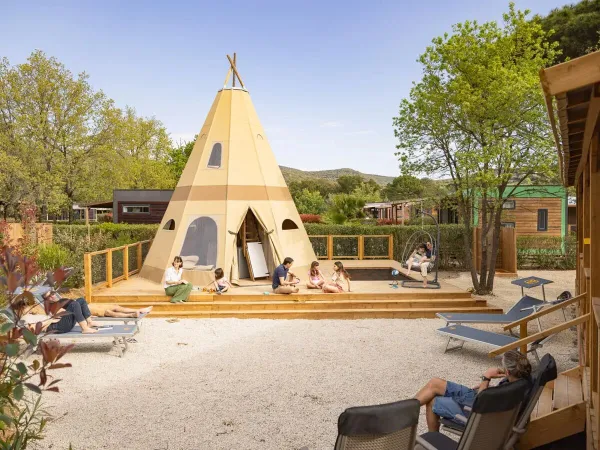Families enjoy the space around the Supreme Deluxe Family Premium Zone at Roan camping Domaine des Naïades.