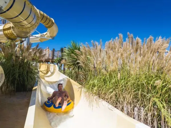 Father has fun sliding down the tyre slide at Roan camping Le Serignan Plage.