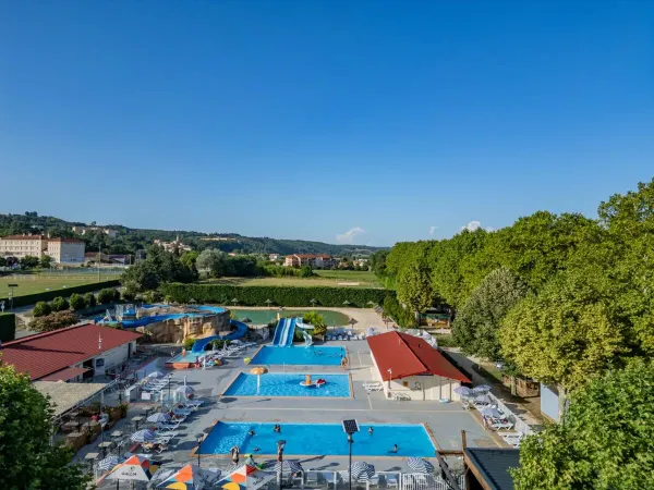 The swimming pool with slides and adjacent terrace at Roan camping Château de Galaure.