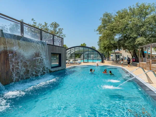 Swimming pool with waterfall and sprinklers at Roan campsite Domaine de Massereau.