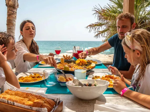 A family sits eating by the beach at Roan campsite Alannia Els Prats.