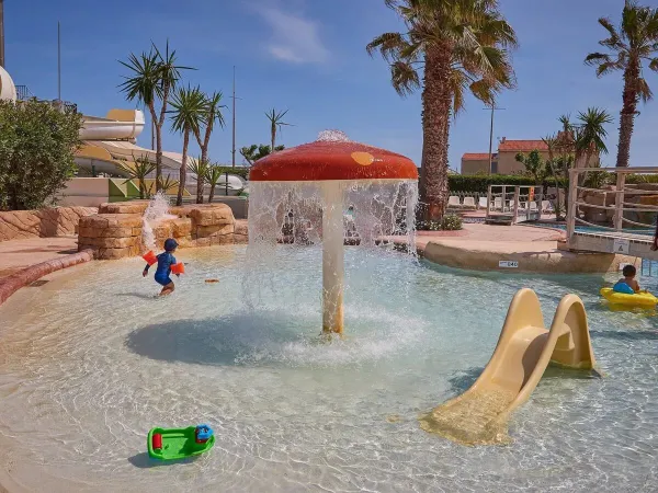 Kids' pool with slide and mushroom sprinkler at Roan campsite Le Petit Mousse.