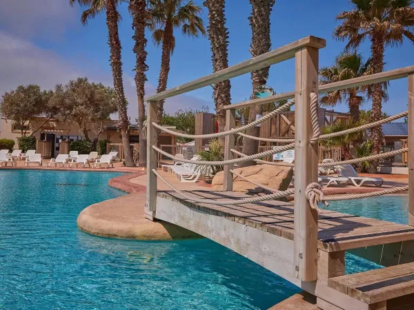 Bridge and loungers by the pool at Roan campsite Le Petit Mousse.
