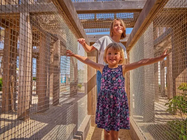 Girls have fun while climbing in the climbing frame at Roan campsite Le Petit Mousse.