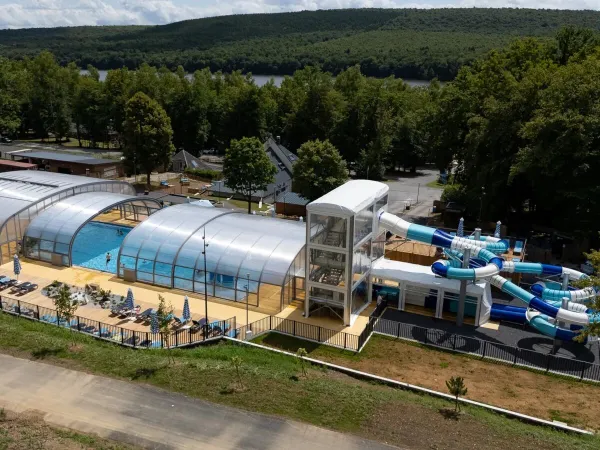 Overview swimming pool with slides and sunbeds at Roan camping Le Lac des Vieilles Forges.