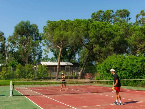 Husband and wife play a game of tennis at Roan campsite Arinella Bianca.