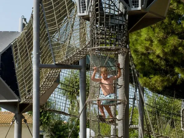 Child climbs the fun rope play equipment atRoan campsite Les Sables d'Or.