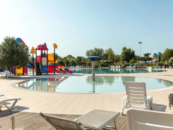 Swimming pool with loungers and playground at Vigna sul Mar campsite.
