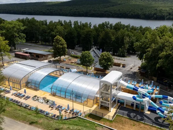Overview swimming pool with slides and sunbeds at Roan camping Le Lac des Vieilles Forges.