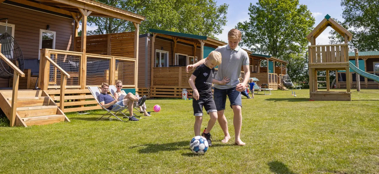Kids playing football in front of a mobile home at a Roan campsite.