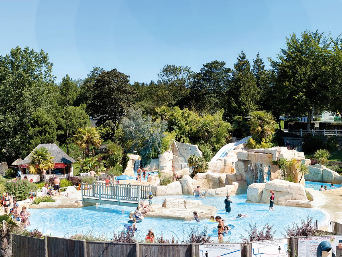 A bustling water park with slides, rock formations, and lush greenery.